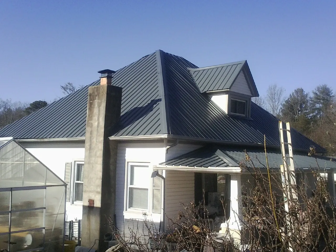 Dark blue standing seam metal roof on a white farmhouse with dormer — Slate & Tile Roof Repair by Roofing Brothers in Adams Run
