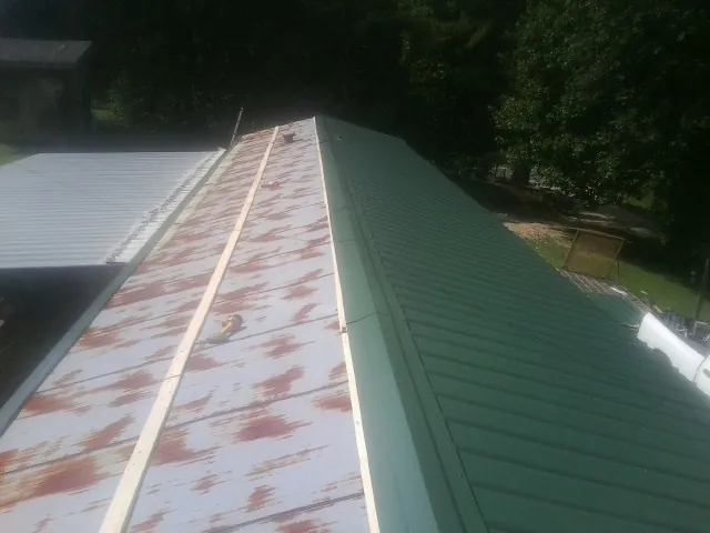 Old rusted panels beside newly installed green metal roofing — Wind Damage Roof Repair by Roofing Brothers in Adams Run