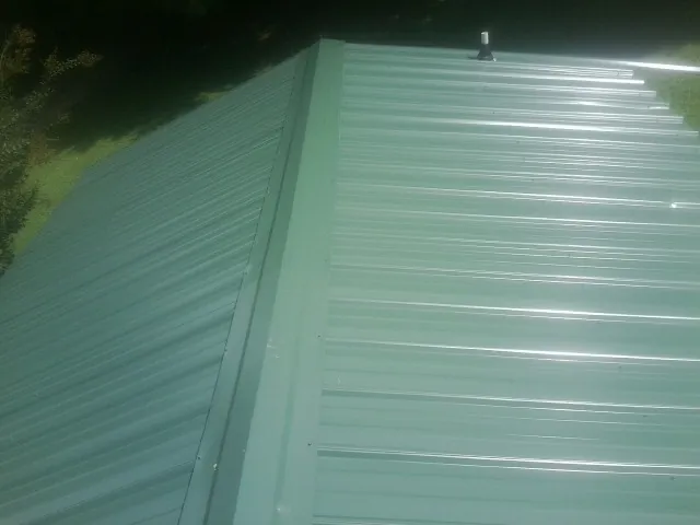 New green metal panels meeting at the ridge of a roof — Flat Roof Repair work by our crew in Adams Run