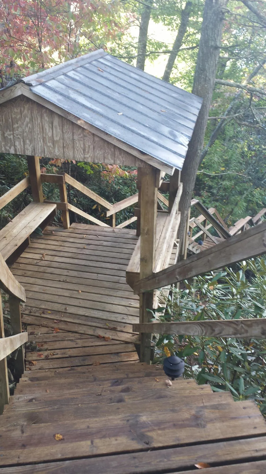Metal roofed shelter over wooden steps on a wooded walkway — Skylight Repair & Installation work by our crew in Adams Run
