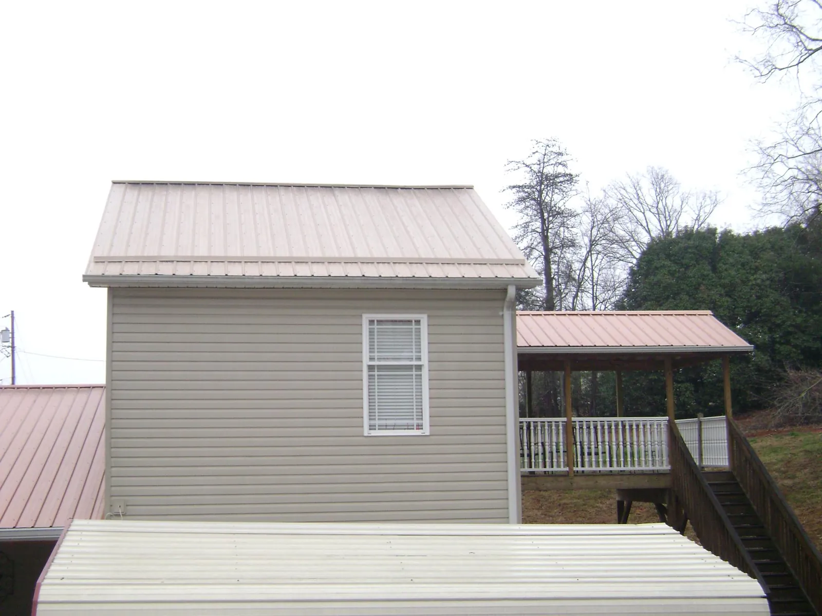 Tan metal roofs on a two story addition and attached porch, from a Roof Replacement job in Adams Run