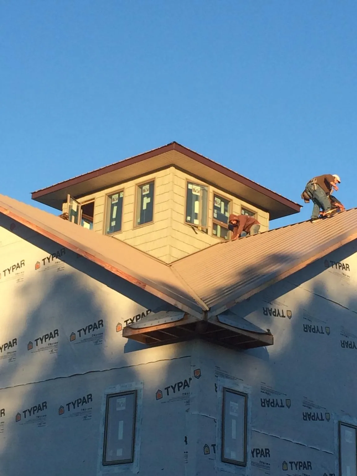 Roofers working around a rooftop cupola on a new metal roof at sunset — Roof Waterproofing in Adams Run by Roofing Brothers